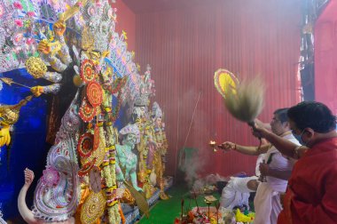 Howrah, Batı Bengal, Hindistan - 25 Ekim 2020: Dhaaks çalınırken tanrıça Durga 'ya aarti sırasında maskeli Hindu rahip tarafından kutsal odalarla tapılıyor. Puja, Corona salgınıdır..