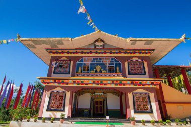 Renkli Buddist dua bayraklarıyla güzel Rinchen Chholing Manastırı, berrak mavi gökyüzü ve arka planda Himalaya dağları. Rinchenpong, Sikkim, Hindistan.