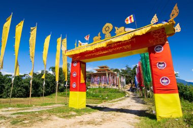 Renkli Buddist dua bayraklarıyla Rinchen Çukur Manastırı 'na güzel renkli bir kapı, açık mavi gökyüzü ve arka planda Himalaya dağları. Rinchenpong, Sikkim, Hindistan.