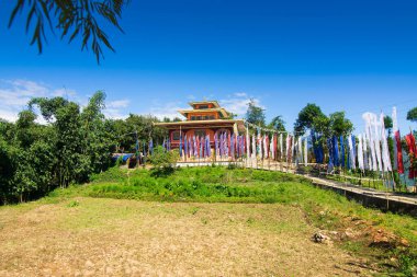 Renkli Buddist dua bayraklarıyla güzel Rinchen Chholing Manastırı, berrak mavi gökyüzü ve arka planda Himalaya dağları. Rinchenpong, Sikkim, Hindistan.