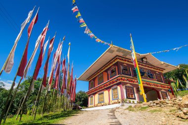 Renkli Buddist dua bayraklarıyla güzel Rinchen Chholing Manastırı, berrak mavi gökyüzü ve arka planda Himalaya dağları. Rinchenpong, Sikkim, Hindistan.
