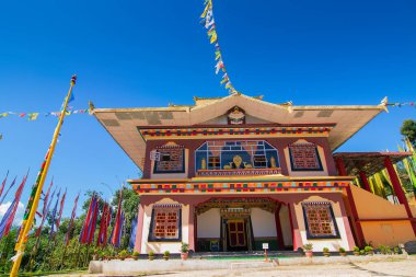 Renkli Buddist dua bayraklarıyla güzel Rinchen Chholing Manastırı, berrak mavi gökyüzü ve arka planda Himalaya dağları. Rinchenpong, Sikkim, Hindistan.