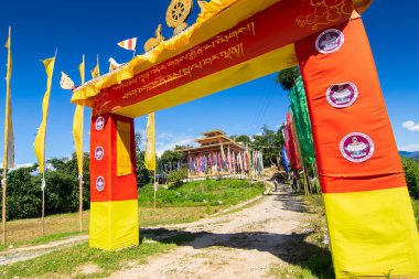 Renkli Buddist dua bayraklarıyla Rinchen Çukur Manastırı 'na güzel renkli bir kapı, açık mavi gökyüzü ve arka planda Himalaya dağları. Rinchenpong, Sikkim, Hindistan.