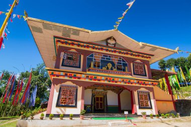 Renkli Buddist dua bayraklarıyla güzel Rinchen Chholing Manastırı, berrak mavi gökyüzü ve arka planda Himalaya dağları. Rinchenpong, Sikkim, Hindistan.