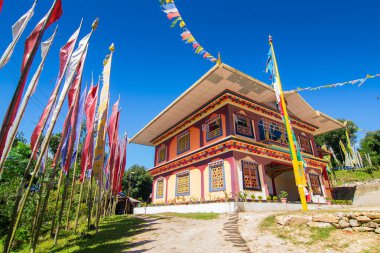 Renkli Buddist dua bayraklarıyla güzel Rinchen Chholing Manastırı, berrak mavi gökyüzü ve arka planda Himalaya dağları. Rinchenpong, Sikkim, Hindistan.