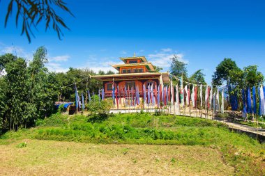 Renkli Buddist dua bayraklarıyla güzel Rinchen Chholing Manastırı, berrak mavi gökyüzü ve arka planda Himalaya dağları. Rinchenpong, Sikkim, Hindistan.