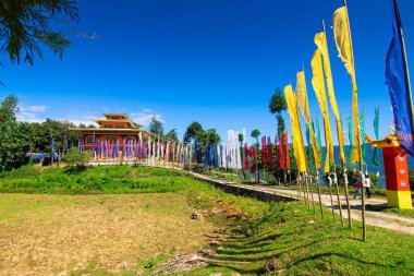 Renkli Buddist dua bayraklarıyla güzel Rinchen Chholing Manastırı, berrak mavi gökyüzü ve arka planda Himalaya dağları. Rinchenpong, Sikkim, Hindistan.