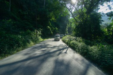 Sikkim, Hindistan - 15.10.2016: Sikkim 'e giderken turistleri ve bavullarını taşıyan araçlar. Yeşil orman ağaçlarının arasından geçen güneş ışığı Himalaya dağlarının içinden geçen yolun doğal güzelliği..