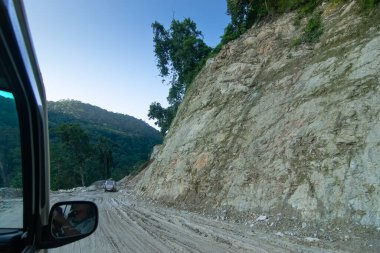 Sikkim, Hindistan - 15.10.2016: Sikkim yolu üzerindeki Himalaya dağlarında yeniden inşa edilmiş yoldan geçen araba. Küresel ısınma, şiddetli yağış ve iklim değişikliğinin etkileri.