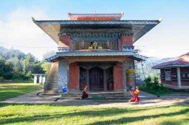 Rinchenpong, Sikkim, Hindistan - 18.10.2016: Rinchenpong Manastırı önünde oynayan kırmızı elbiseli Budist rahipler ve çocuklar. Çocukluk sevinci. Arka planda Himalaya Dağları.
