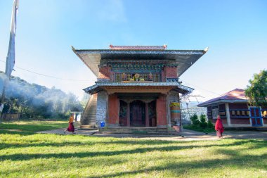 Rinchenpong, Sikkim, Hindistan - 18.10.2016: Rinchenpong Manastırı önünde oynayan kırmızı elbiseli Budist rahipler ve çocuklar. Çocukluk sevinci. Arka planda Himalaya Dağları.
