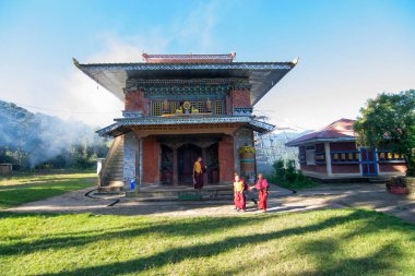 Rinchenpong, Sikkim, Hindistan - 18.10.2016: Rinchenpong Manastırı önünde oynayan kırmızı elbiseli Budist rahipler ve çocuklar. Çocukluk sevinci. Arka planda Himalaya Dağları.