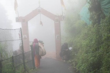 Darjeeling, Batı Bengal, Hindistan - 22.07.2023: Mahakal Tapınağı ya da Mahakal Mandir, Hindu tanrısı Shiva tapınağı ve Hindu ve Budist dinlerinin bir karışımıdır. Sis ile yemyeşil yol.