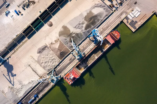 An aerial drone view of the industrial port in the Baltic Sea. There is a ships under load in the harbor.