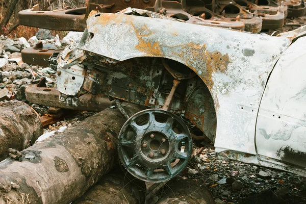 一辆在大型金属管背景的废品堆场发生严重事故后烧毁的汽车 — 图库照片