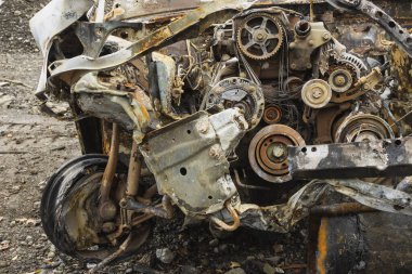 Hurdalıkta meydana gelen ağır bir kazadan sonra yanmış bir araba. Yakından geçen bir araba motoru..