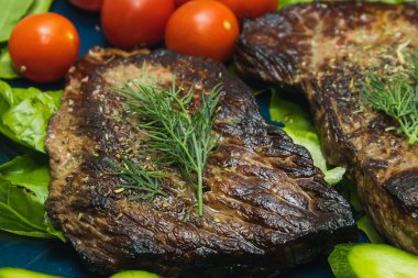 Salatalık, domates ve bitkilerle dolu bir tabakta biftek..