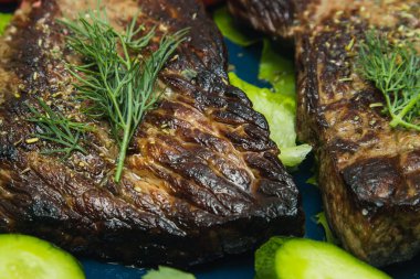 Salatalık, domates ve bitkilerle dolu bir tabakta biftek..