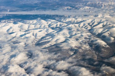 Kuş bakışı karlı dağlar açık mavi gökyüzünde bulutlu.