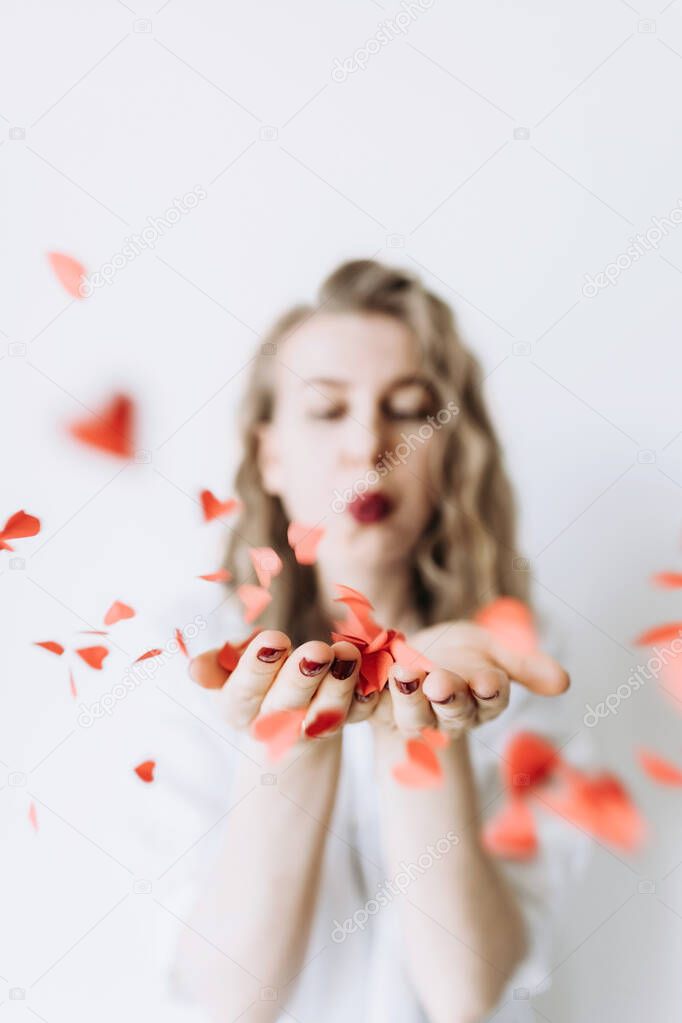 A happy woman blows a lot of red hearts from her palm and they fly away.Happy Valentines day.The concept of love and friendship.Concept of heart health and organ donation.Close-up