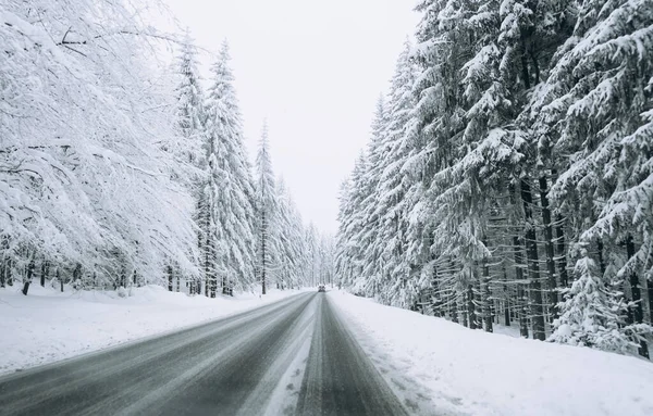 A road on the background of a beautiful winter snow-covered landscape.Family trip, vacation, adventure. Driving a car in extreme winter conditions.Travel concept background