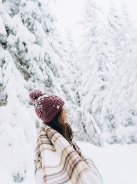 Young happy girl enjoys winter, frosty day, snow, on the background of a snow-covered landscape.The winter lifestyle.Individual winter adventures.Rest during the Christmas holidays.healthy break