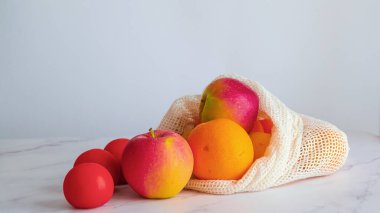 Farklı meyve ve sebzeler beyaz bir masada, bez bir torbanın içinde. Sürdürülebilir alışveriş ve plastiksiz satın alma kavramı. Boşluğu Kopyala