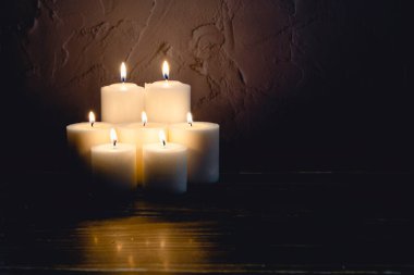 Siyah arkaplan ile yanan yedi mum grubu. Rahatlık kavramı, maneviyat, mistisizm, din, ölülerin anısı. Ölüler Günü. Dikey fotoğrafçılık ve kopyalama alanı