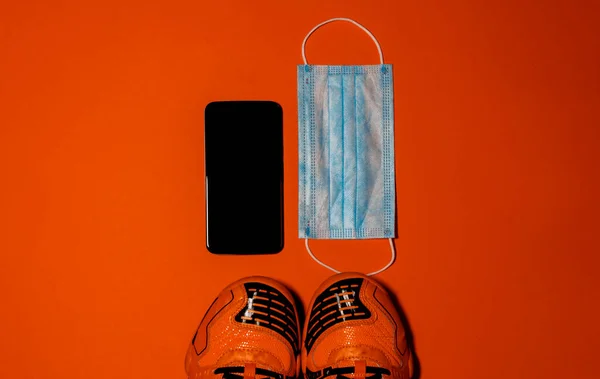Foto Aérea Zapatillas Naranjas Smartphone Máscara Quirúrgica Sobre Fondo Naranja —  Fotos de Stock