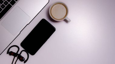 Evden çalışma alanının yukarıdan çekimleri: laptop, akıllı telefon, kulaklık ve bir fincan kahve. Ev kavramından çalış. Boşluğu Kopyala