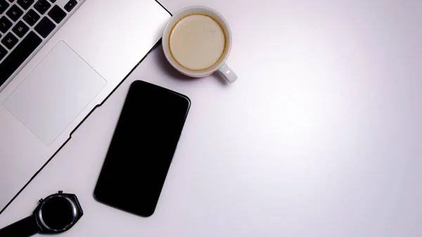 Overhead shot of a workspace from home: laptop, smartphone, smartwatch and a cup of coffee. Work from home concept. Copy Space