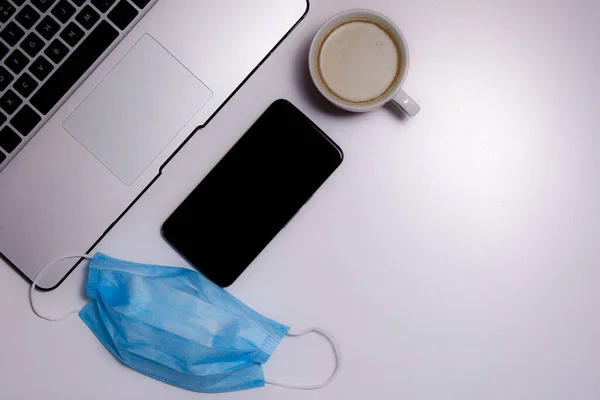 Blick Über Den Arbeitsplatz Laptop Smartphone Maske Und Eine Tasse — Stockfoto