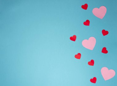 Açık mavi arka planda birkaç kırmızı ve pembe kalbin yukarıdan çekimi. Sevgililer Günü için arka plan. Yatay fotoğrafçılık ve kopyalama alanı