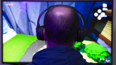 Ekranın önünde video oyunu oynayan bir adamı yakından çek. Oyuncu ve e-spor konsepti. Dikey fotoğrafçılık ve kopyalama alanı.