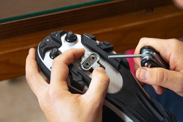 Close-up of a man's hands assembling his cycling carbon road shoes and attaching cleats for pedals. Sport concept, preparation for cycling.