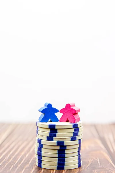 Gender pay equality concept. Blue doll representing a man and pink doll representing a woman on a stack of coins.