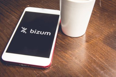 İspanya, 02, 03, 2021. Bizum uygulamalı ev ekranlı bir akıllı telefonun beyaz bir fincan kahvenin yanında detaylı görüntüsü. Bir kahve dükkanında akıllı telefonlu acil ödeme kavramı.