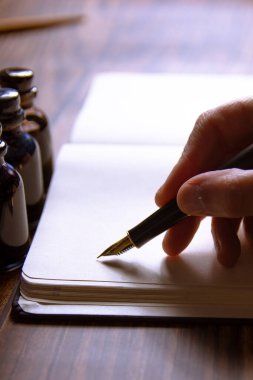 Bir defter ve birkaç mürekkep hokkası üzerine bir dolmakalem yakın plan.