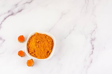 Aynı bitkinin birden fazla kökü mermer bir masada bulunan zerdeçal tozu dolu bir kase. Doğal tıp ve homeopati kavramı