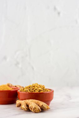 Mermer bir masanın üzerinde toz ve zencefil kökü olan birkaç kil kaseli bir arka plan. Doğal tıp ve homeopati kavramı
