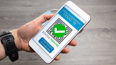 Sağlık pasaportu. Şifreli aşı sertifikası ya da akıllı telefon ekranında ameliyat maskesi, güneş gözlüğü ve masada hidro alkollü jel ile aşı pasaportu.