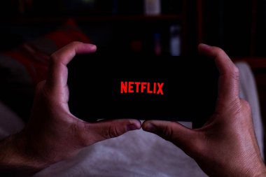İspanya. 04, 18, 2021. Kanepesinde Netflix ekranı olan akıllı telefonu olan bir adamın yakın plan fotoğrafı.