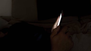 Akşamları akıllı telefonunu kullanan bir adamın yakın çekimi. Uykusuzluk konsepti. Gece mobil aygıtların kullanımı