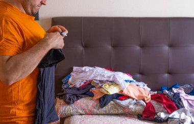 Evinde çamaşırları katlayan bir adam. Ev işlerinde cinsiyet eşitliği