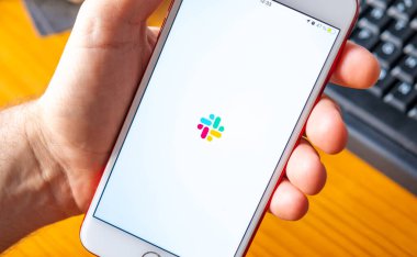 Estremadura. 07, 22, 2021. Ekranda Slack uygulaması olan iPhone 'u tutan bir el. Çalışma ve zaman yönetimi uygulaması