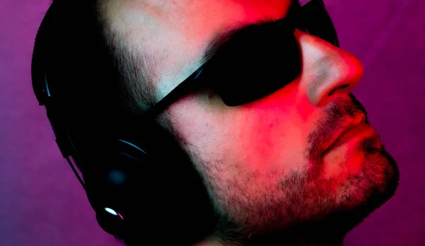 Neon portrait of a caucasian man wearing sunglasses and with headphones listening to music. Listen to music