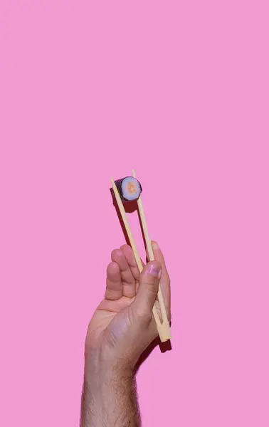 Рука Чоловіка Тримає Суші Японськими Паличками Рожевому Фоні Суші Японська — стокове фото