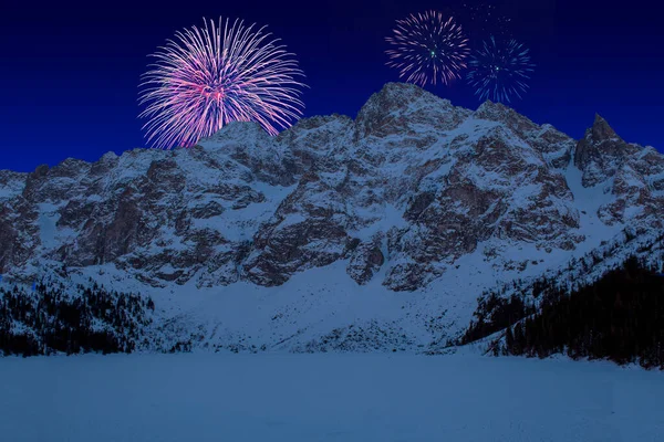 Celebratory fireworks for new year over Tatra National Park, Zakopane Poland. Famous Mountains Lake Morskie Oko Or Sea Eye during last night of year. Christmas atmosphere. Snow above it and mountain