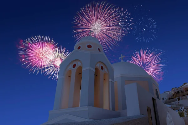 Santorini 'deki ortodoks beyaz kilisesinin üzerinde yılın son gecesi için havai fişek kutlaması. Noel atmosferi. 
