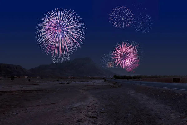 Celebratory fireworks for new year over the moroccon desert near ouarzazate  during last night of year. Christmas atmosphere.  Street or road in close up and mountain in background